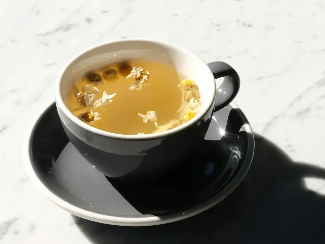 Cup of chamomile tea beside dried chamomile flowers